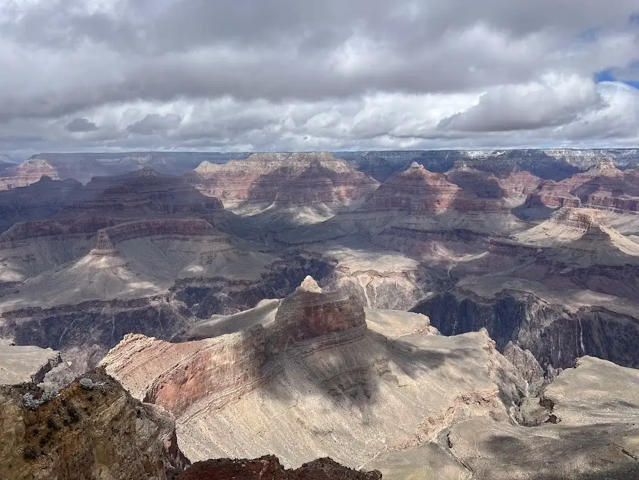 A Photo of the Grand Canyon looking north with clouds and snow in the background.